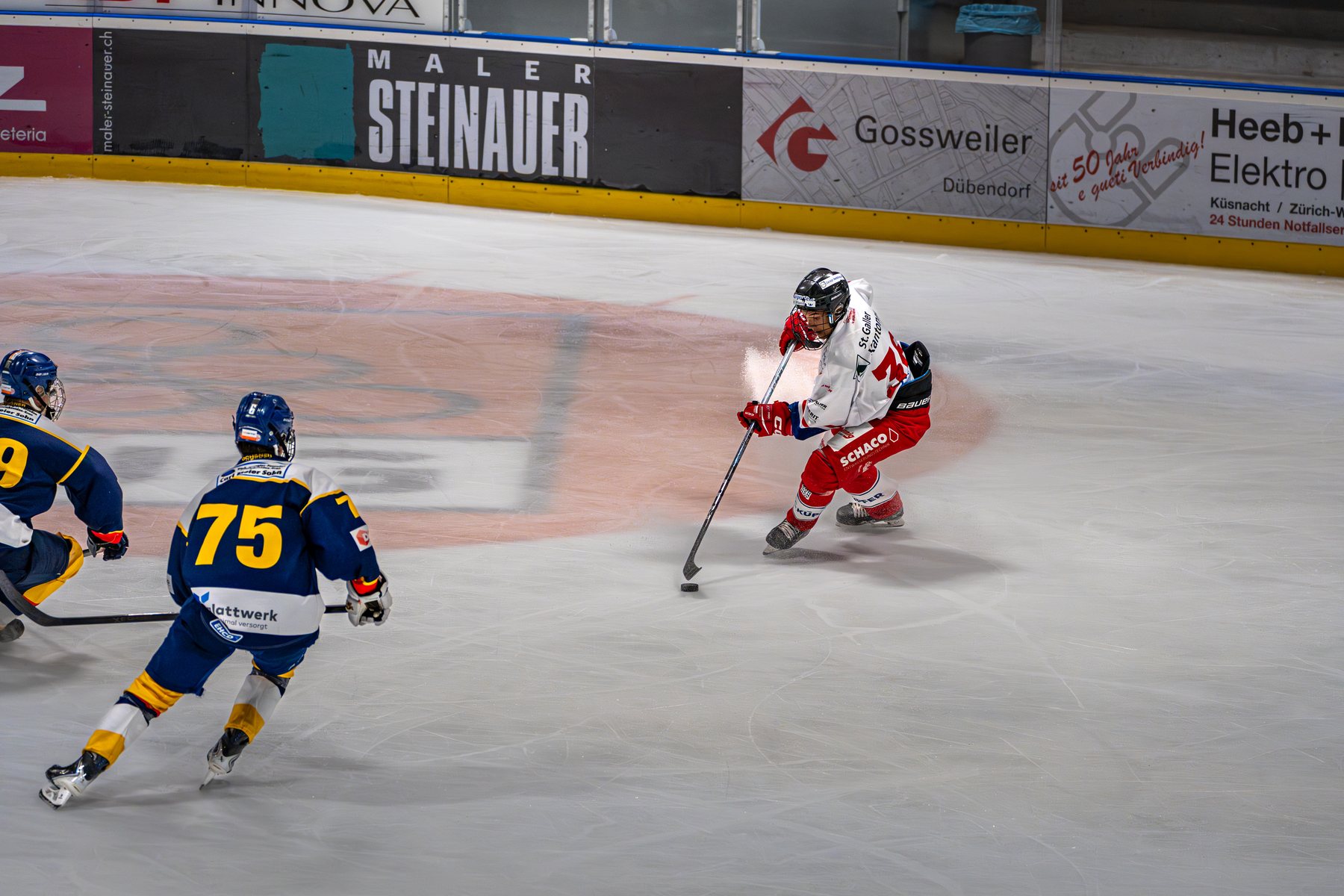 Rapperswiler Spieler läuft mit dem Puck auf zwei Dübendorfer zu