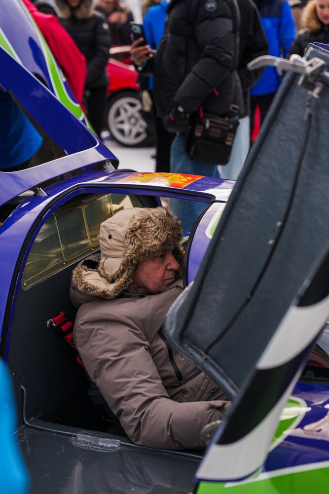 Fahrer mit Fellmütze im Cockpit eines Rennwagens