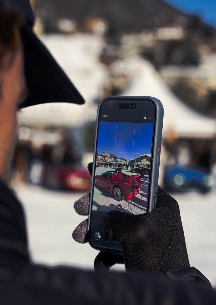Besucher fotografiert einen roten Ferrari mit dem Smartphone